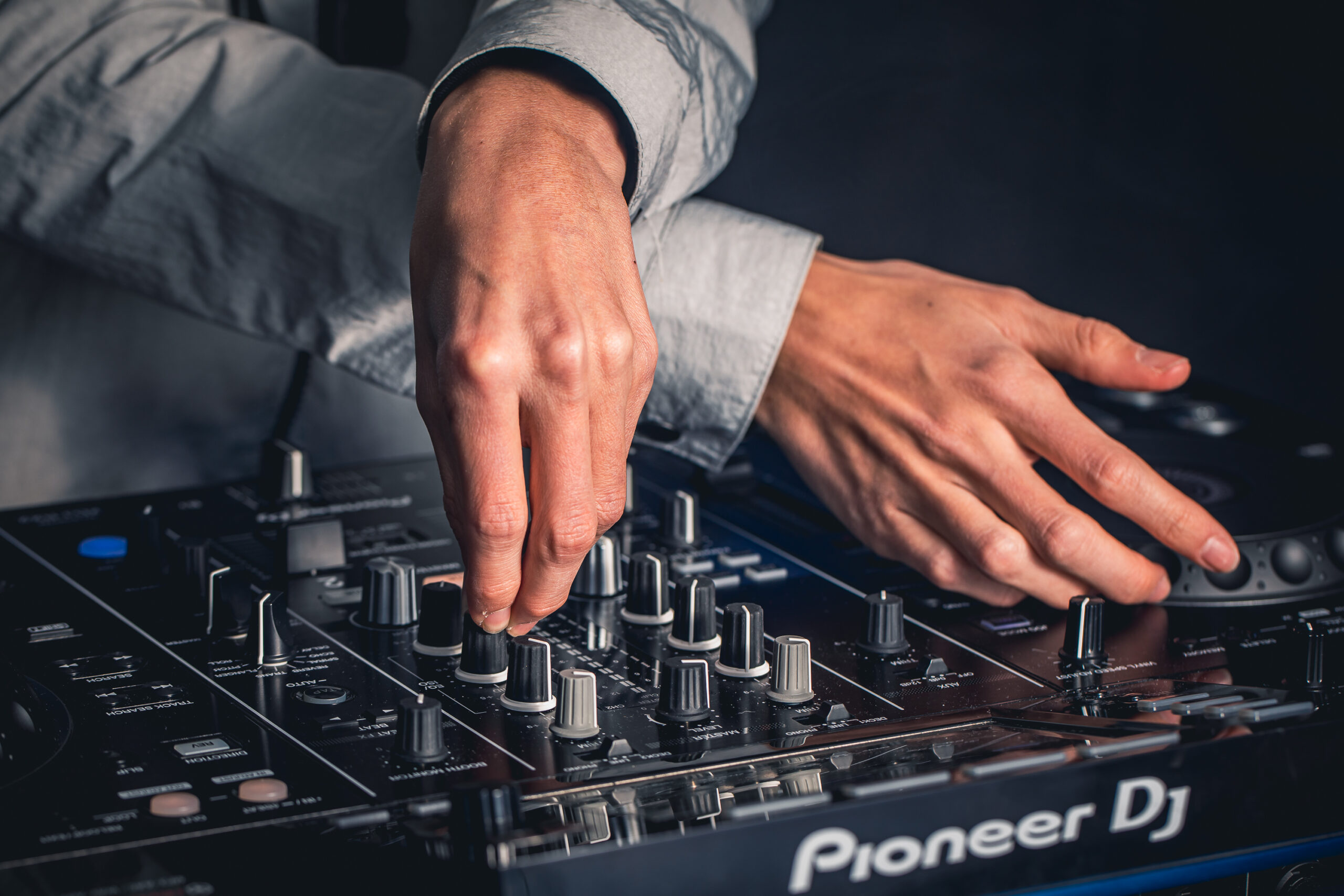 Main d’un DJ entrain de mixer sur un contrôleur DJ pioneer XDJRX2 de couleur noir.